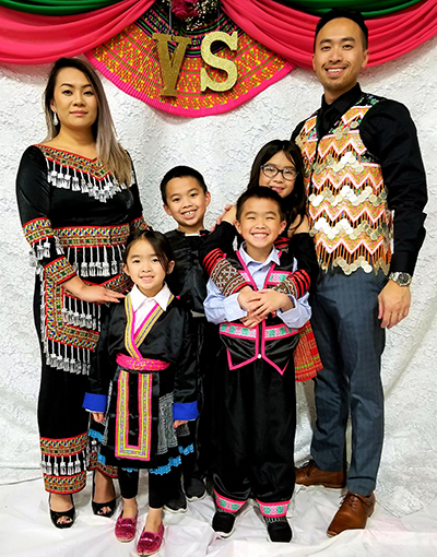 alvin Yang M’17 and his wife, Zong (M’11), pose with their four children while wearing traditional Hmong clothing.