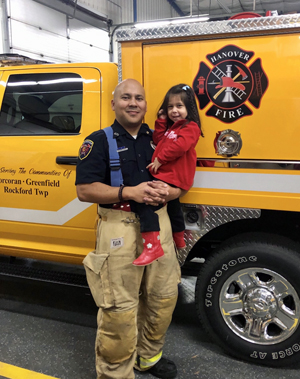 George Diaz stands next to one of the Hanover Fire Department trucks with his daughter, Nora.