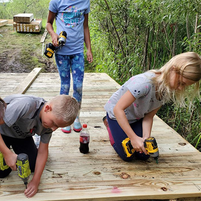 Fourth grader Nate Fuglestad and third grader Avery Olson help construct part of the bridge/boardwalk behind Discovery Middle School. They were just two of the students Lukas Gotto enlisted to help with the project.