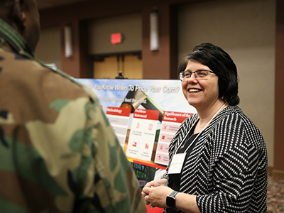 Jenifer Zinsmaster speaks with someone about her research at the 16th annual Doctoral Research Symposium on March 7.